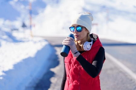 Sportive lady with thermos bottle in winter nature