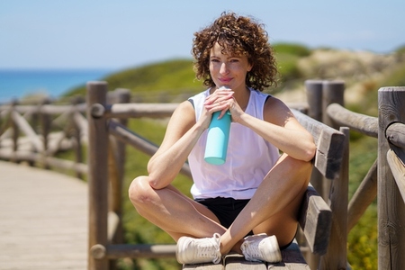 Woman with bottle of water resting after workout