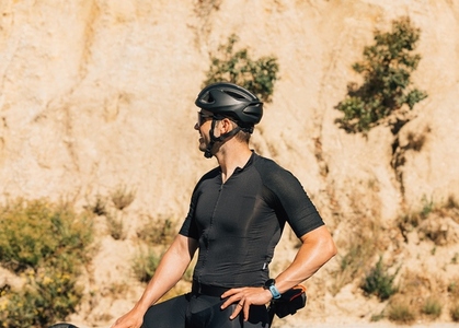 Side view of a professional cyclist in black sports attire looking away and smiling