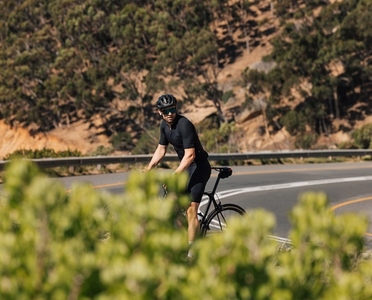 Professional cyclist in black sportswear taking a break on the road during training