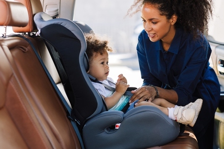 Young mother preparing baby car seat for her son