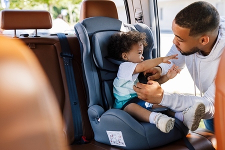 Young father adjusting belt on a baby car seat