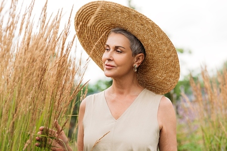 Aged woman in a straw hat on the field at summer