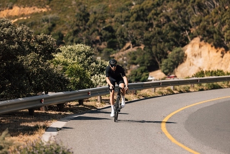Male cyclist riding a bike on an empty mountain road during the day