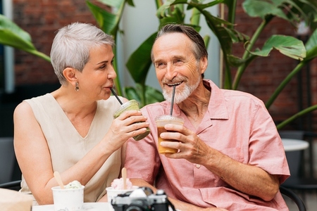 Happy aged couple drinking cocktails in an outdoor cafe  Smiling mature couple enjoying drinks outdoors