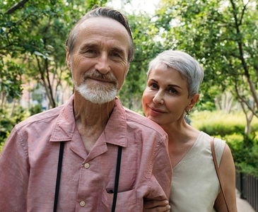 Portrait of an aged couple looking at the camera while standing together in the park