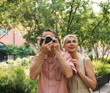 Mature couple taking photos while walking in the park