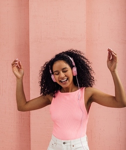 Happy woman wearing pink headphones enjoying music with closed eyes