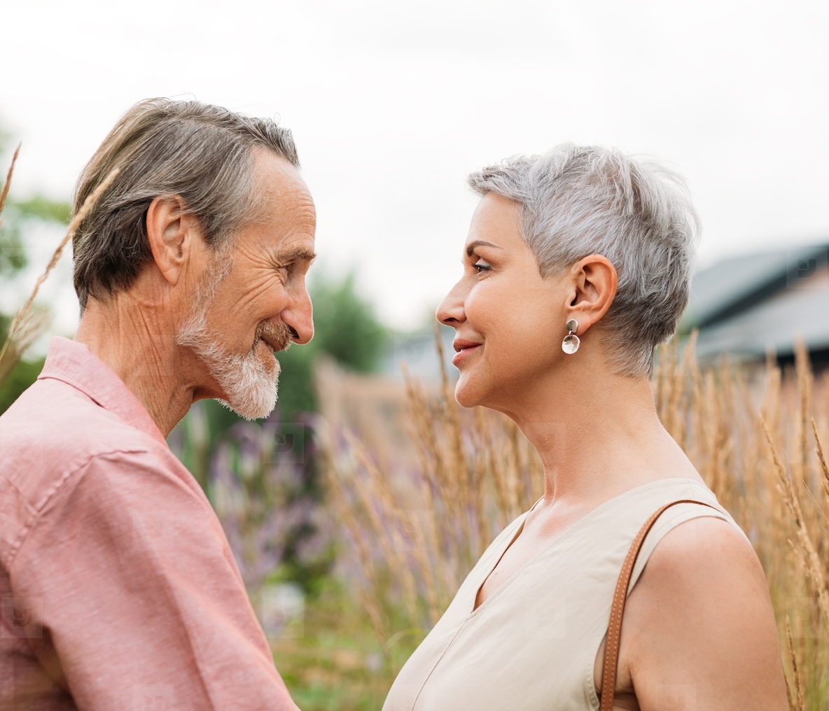 Aged couple looking at each other while standing on a field of wheat