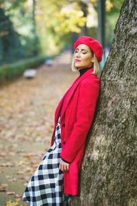 Gentle woman in red outerwear leaning on tree