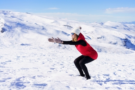Young woman warming up body with exercise on snow