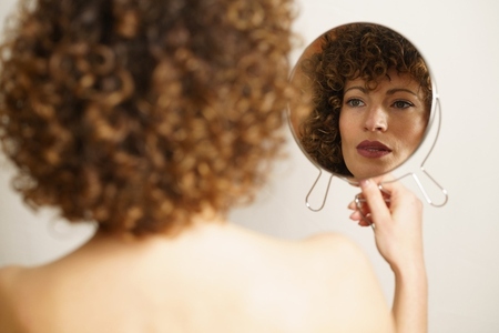 Charming woman with makeup looking reflection in mirror