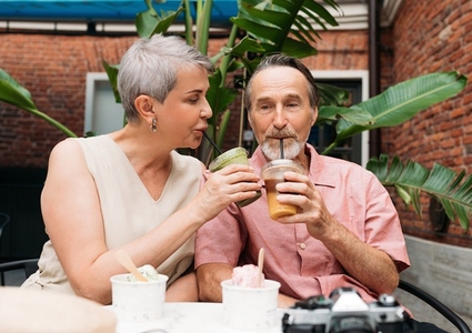 Mature couple sitting in an outdoor cafe and drinking cocktails