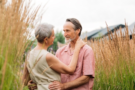 Mature couple hugging each other while standing on a wheat field