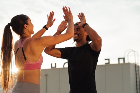 Man and woman doing a high five during a workout routine on the roof
