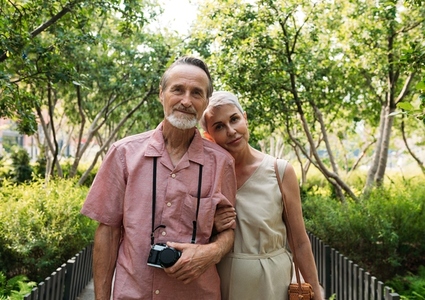 Aged couple standing in the park and looking at camera
