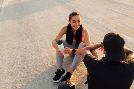 Smiling sportswoman looking at her fitness buddy while they are taking a break