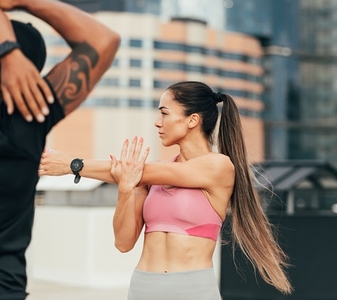 Young female athlete with long hair warming up her hand on a rooftop