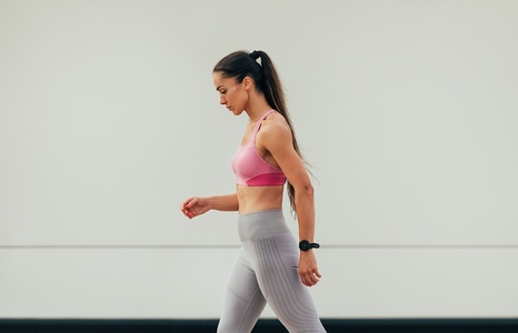 Side view of a slim female preparing to run outdoors  Young woman in fitness attire at a wall