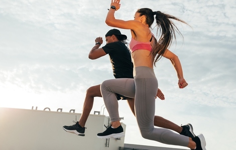 Two athletes jumping in the air during run  Man and woman sprinting together on the roof