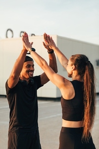 Two athletes in black sportswear giving high five on the roof
