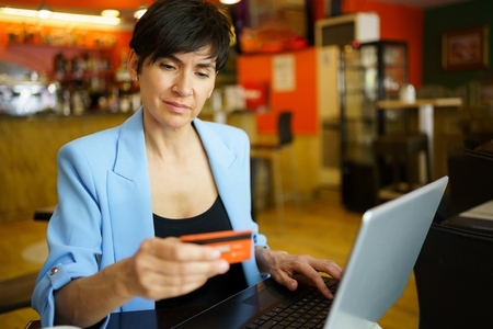 Focused woman using credit card and laptop in cafe