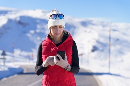 Sportive woman using phone in winter countryside