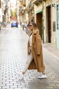 Stylish female in coat crossing street