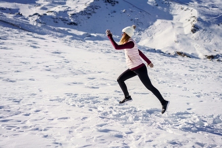 Active woman jogging on snowy terrain