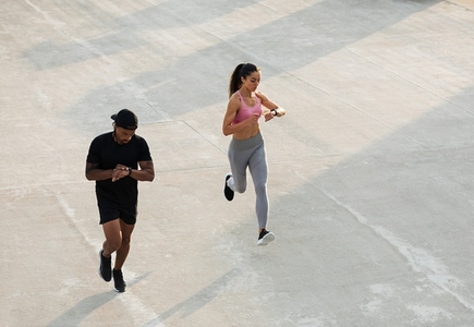 Two athletes checking their smartwatches during a run on the roof