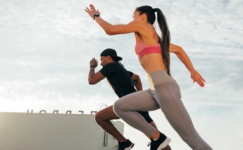 Two runners jumping during a sprint on a rooftop