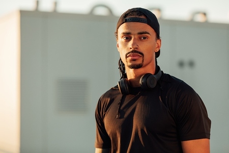 Portrait of a confident male athlete in a cap with headphones