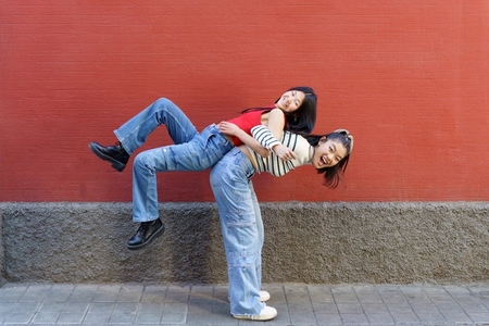 Happy Asian woman lifting friend on back
