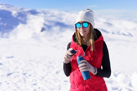 Smiling woman with bottle of water standing on snow