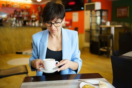 Pensive woman with cup of coffee in cafe