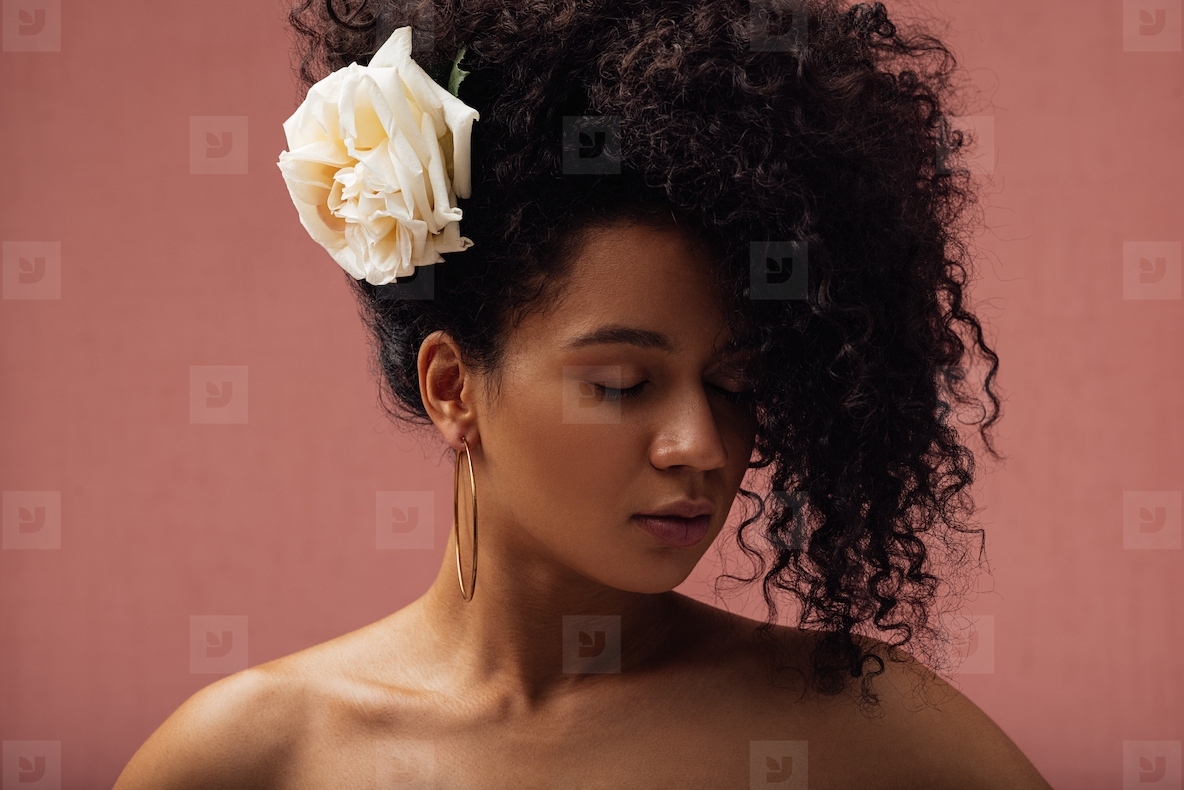 Close up portrait of woman with closed eyes and flower in her curly hair