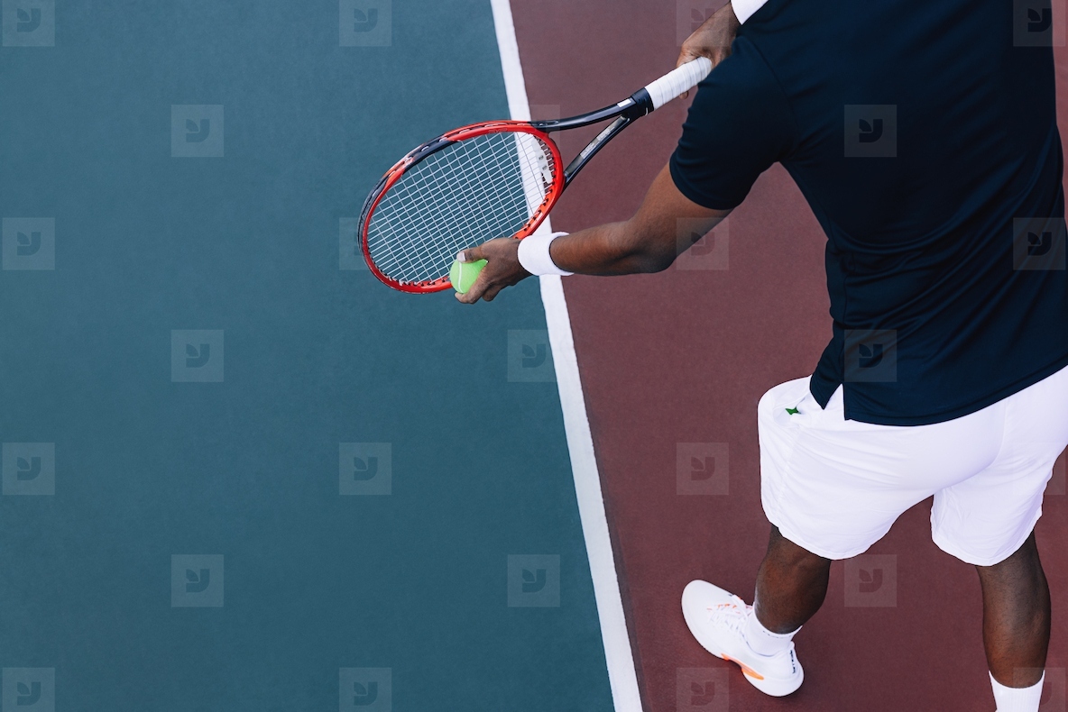 Mid section of a professional tennis player wearing sports clothes, holding a tennis racket, and preparing to hit a ball