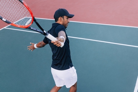 Professional tennis player practicing one handed backhand hit on hard court