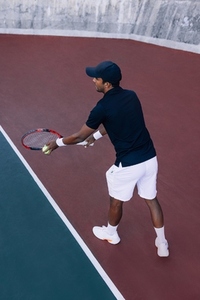 Tennis player with a racket ready to serve a tennis ball standing at the baseline