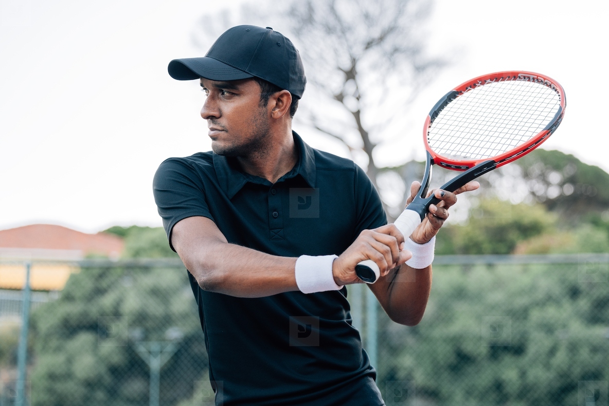 Side view of confident tennis player with racket outdoors