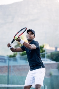 Young tennis athlete preparing to serve the ball in a game on an outdoor court