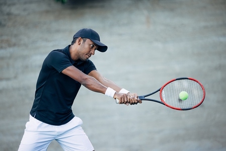 Professional tennis player hitting ball with racket while playing outdoors