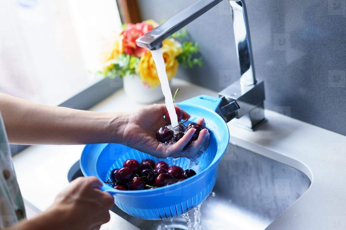 Unrecognizable woman washing cherries in sink