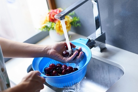 Unrecognizable woman washing cherries in sink