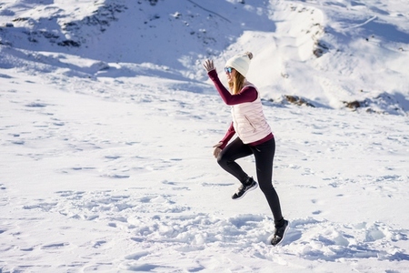 Unrecognizable woman running on snowy terrain in winter