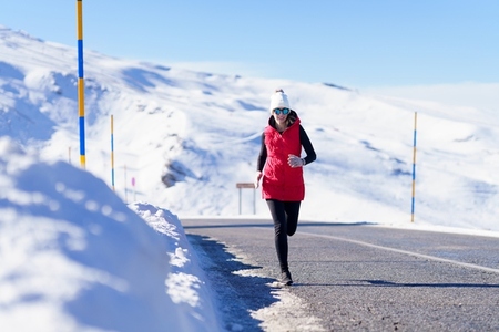 Female running on road in snowy mountains