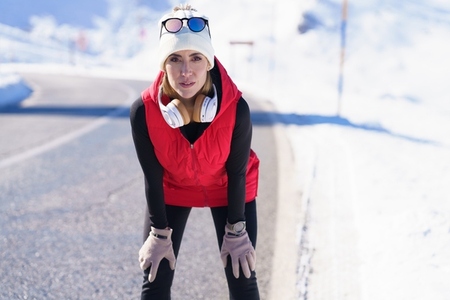 Athletic female in outerwear on road in winter mountains