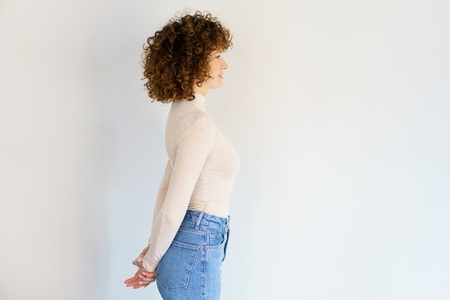 Curly haired woman standing with hands behind back