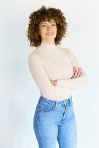 Smiling curly haired woman with hands crossed