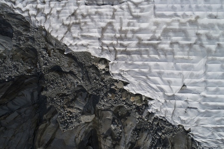 Aerial view textured rocks and protective tarpaulin over Rhone Glacier Switzerland
